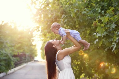 Güzel genç anne holding şirin bebek çocuk, açık havada