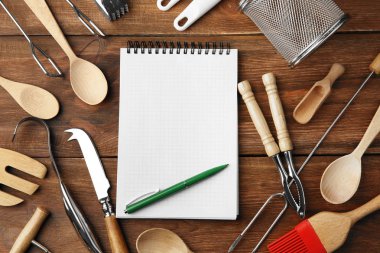 Defter ve ahşap arka plan üzerinde çeşitli mutfak eşyaları