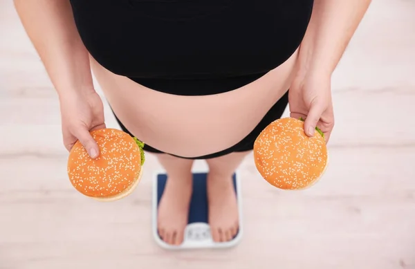 Übergewichtige Frau hält Burger in der Hand — Stockfoto