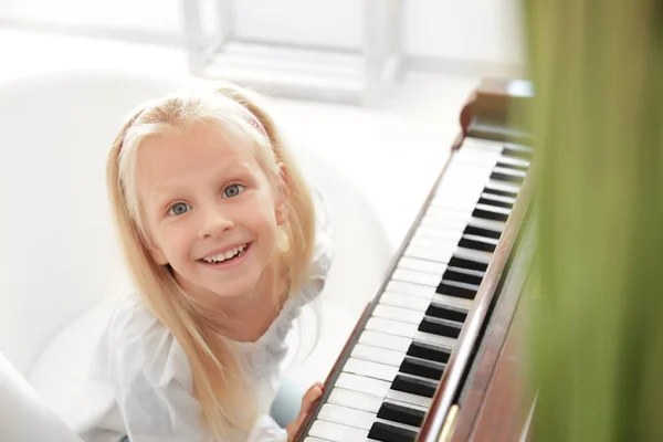 Adorável menina perto de piano dentro de casa — Fotografia de Stock