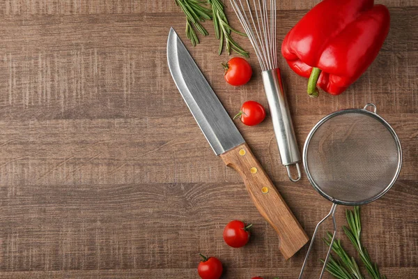Vários utensílios de cozinha e legumes em fundo de madeira — Fotografia de Stock