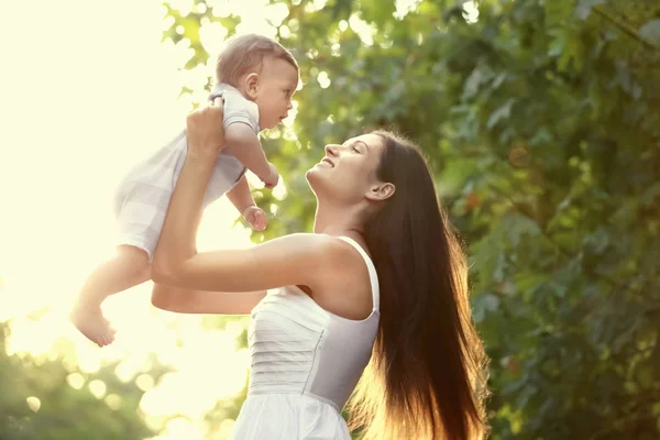 Hermosa madre joven sosteniendo lindo bebé niño, al aire libre —  Fotos de Stock