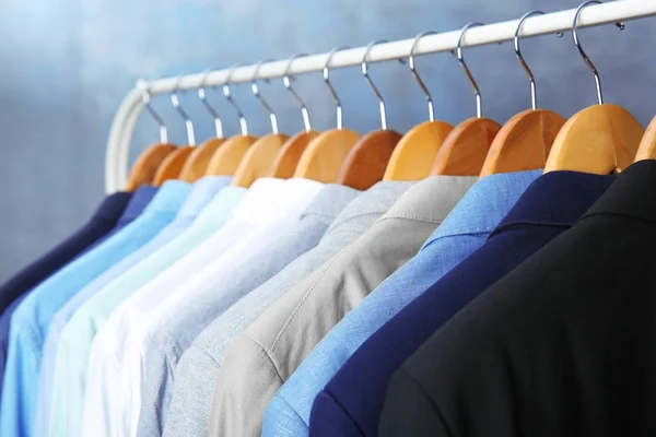 Jackets and shirts hanging on clothing rail — Stock Photo, Image