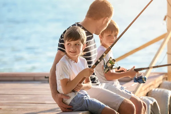 Vader met zonen vissen vanaf de pier op rivier — Stockfoto