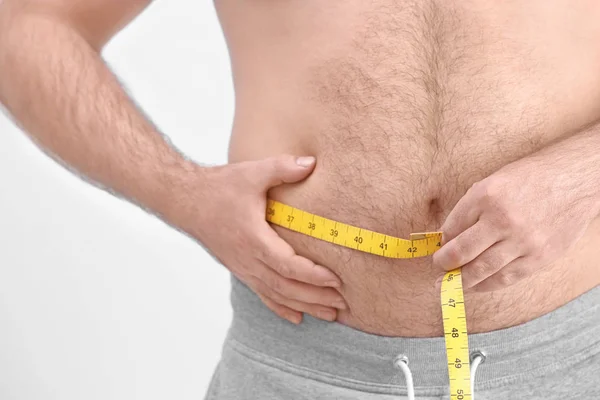 Избыточный вес человека с измерительной лентой — стоковое фото