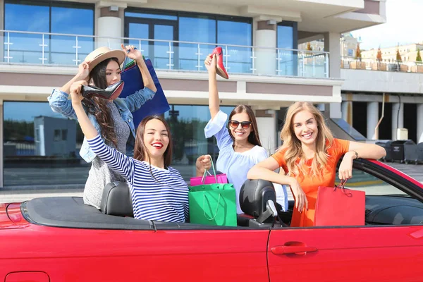 Mooie jonge vrouwen met boodschappentassen in cabriolet buitenshuis — Stockfoto