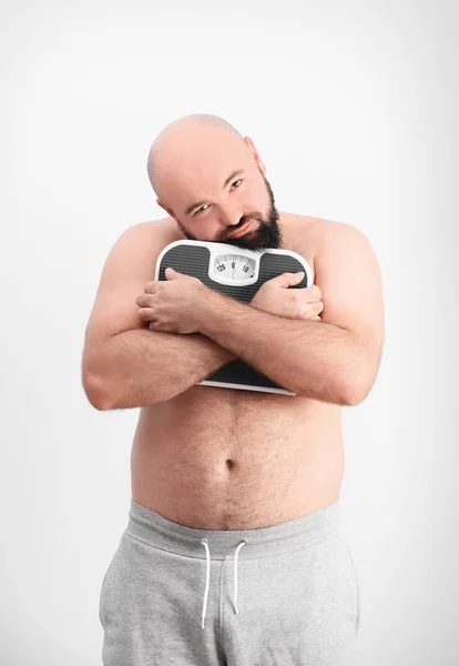 Overweight man hugging scales — Stock Photo, Image