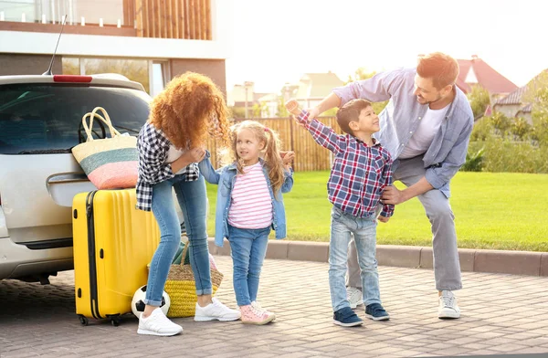 Молодая семья с детьми возле машины — стоковое фото