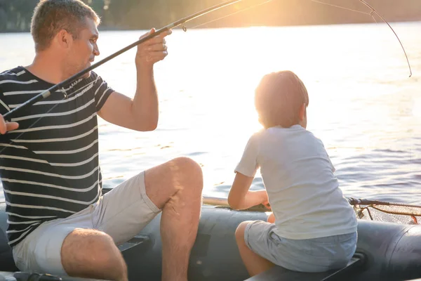 Отец с сыном рыбачит с лодки на реке — стоковое фото