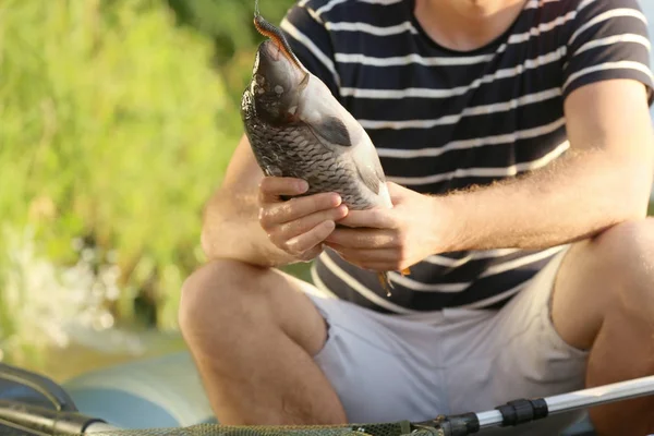 Young man holding fish, outdoors — Stock Photo, Image