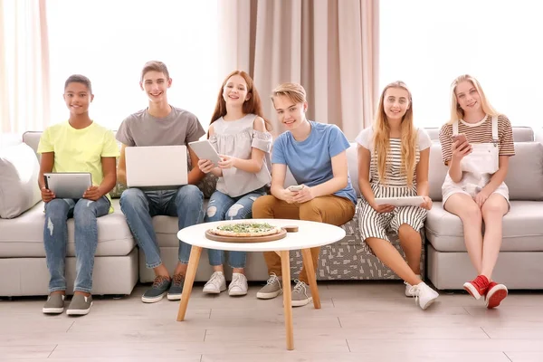 Skupina teenagerů s moderní gadgets a chutnou pizzu doma — Stock fotografie