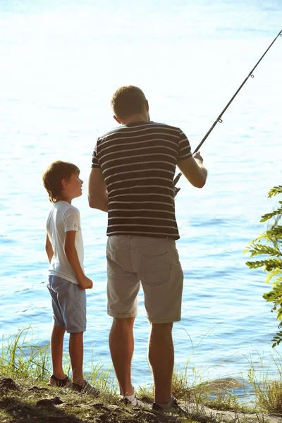 Padre con hijo pesca desde la orilla del río — Foto de Stock