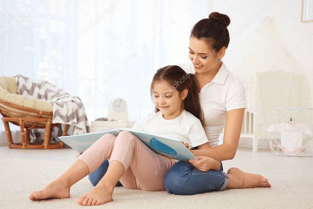 Young mother with daughter reading book