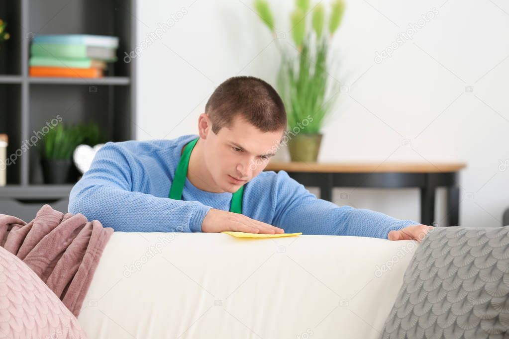 Young man cleaning sofa 