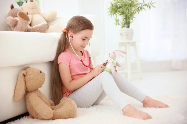 Adorável menina examinando brinquedo — Fotografia de Stock