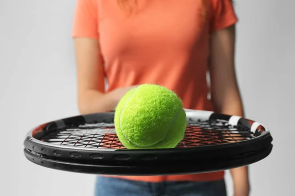 Жінка з тенісною ракеткою і м'ячем на світло-сірому фоні, крупним планом — стокове фото
