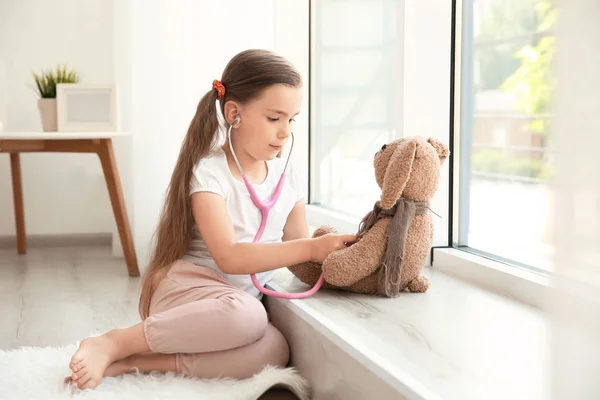 Adorable niña examinando conejito juguete —  Fotos de Stock