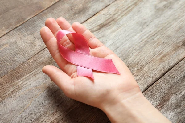 Mano Femenina Sosteniendo Cinta Rosa Sobre Fondo Madera Concepto Cáncer — Foto de Stock