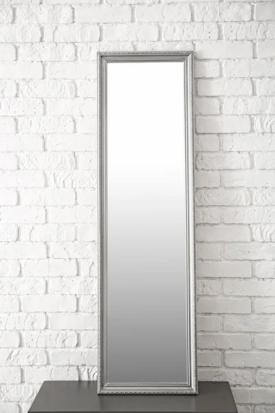 Modern mirror on stand near brick wall — Stock Photo, Image