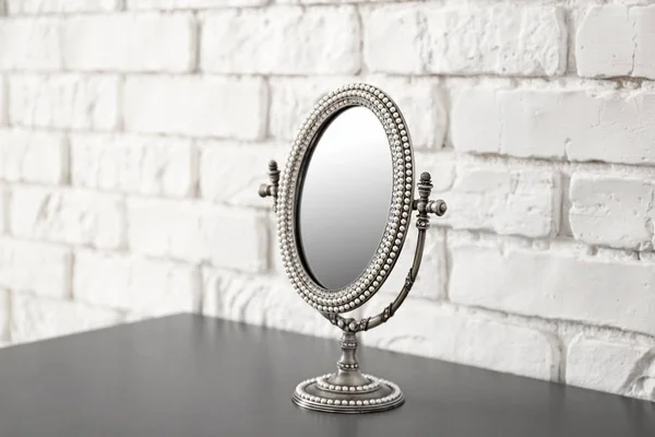 Kleiner Spiegel auf Tisch in der Nähe der Ziegelwand — Stockfoto