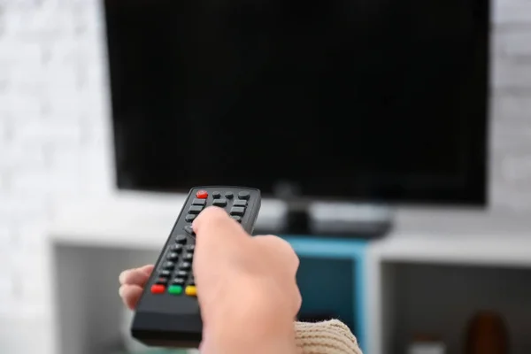 Woman with TV remote control switching channels, closeup — Stock Photo, Image