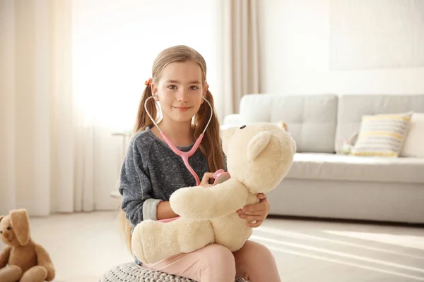 Adorável menina examinando ursinho — Fotografia de Stock