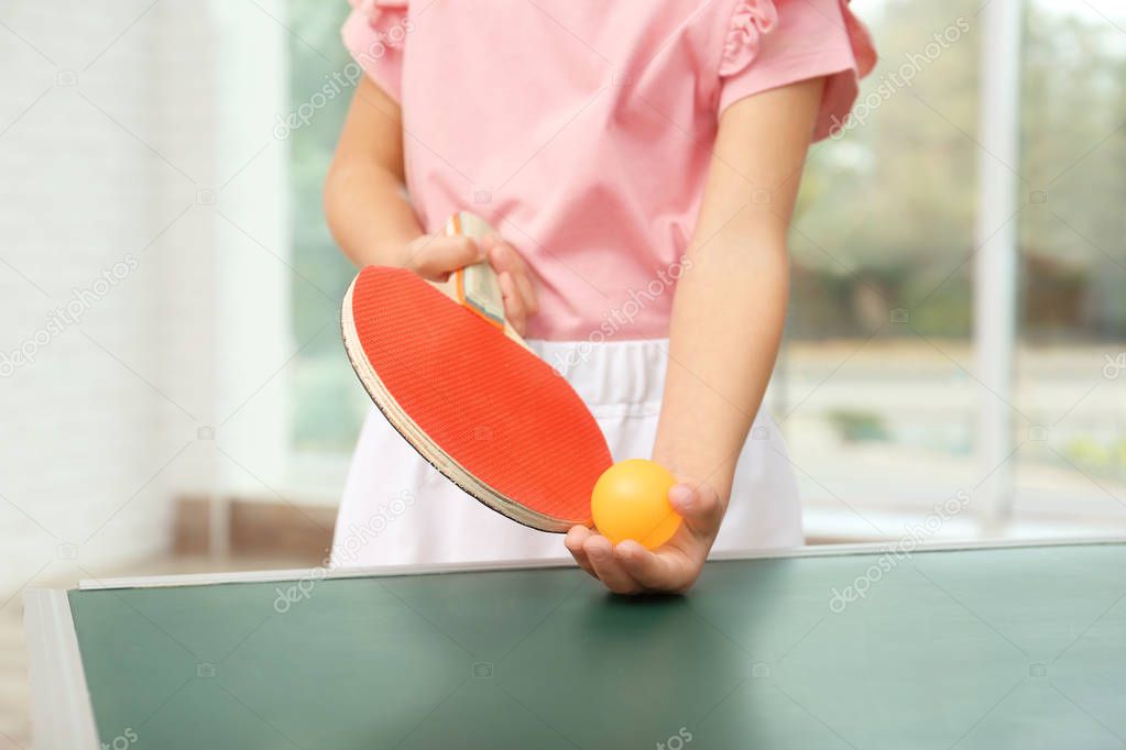 Cute little girl playing table tennis indoors