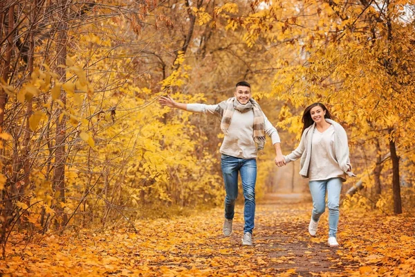 Молодая пара бегает по аллее парка осенью — стоковое фото