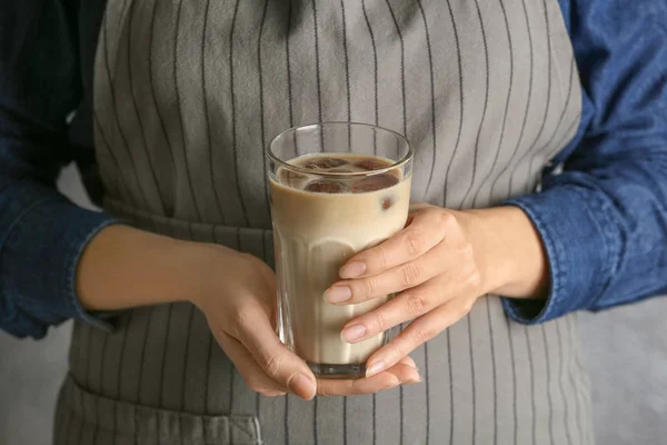 Женщина в фартуке держит стакан с вкусным кофе — стоковое фото