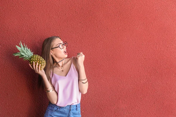 Attraente ragazza hipster in posa con ananas su sfondo di colore — Foto Stock