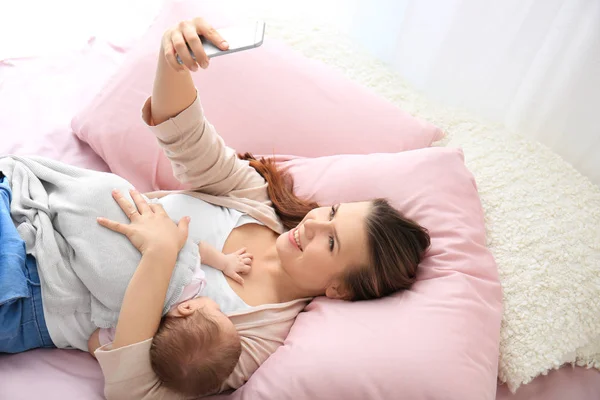 Молода мати бере селфі з дитиною на ліжку вдома — стокове фото