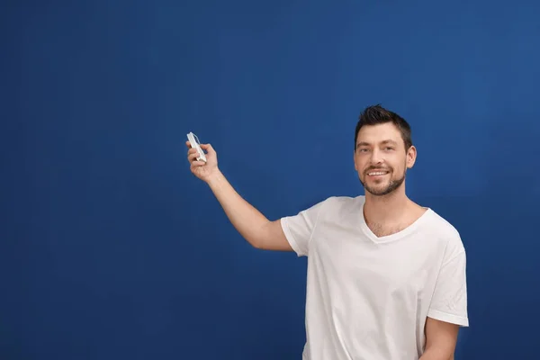 Bonito homem ligando ar condicionado contra fundo azul — Fotografia de Stock