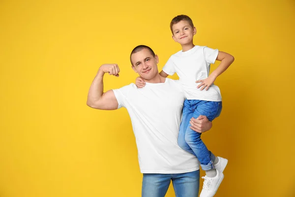 Papá y su hijo mostrando músculos en el fondo de color —  Fotos de Stock