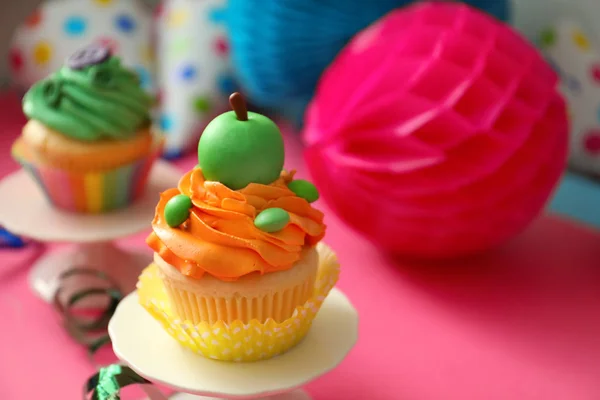 Stå med välsmakande ljusa cupcake på färgbakgrund — Stockfoto