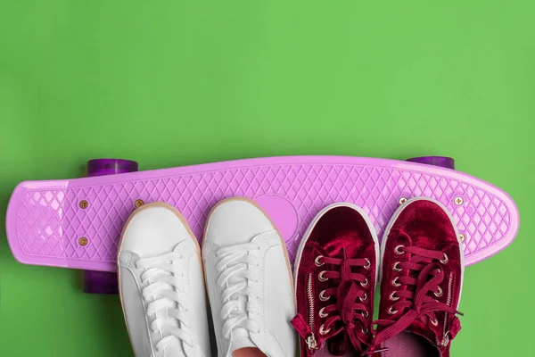 Female sport shoes with skateboard on color background — Stock Photo, Image