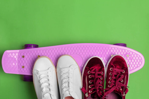 Female sport shoes with skateboard on color background