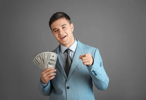Красивий бізнесмен з доларовими купюрами на сірому фоні — стокове фото