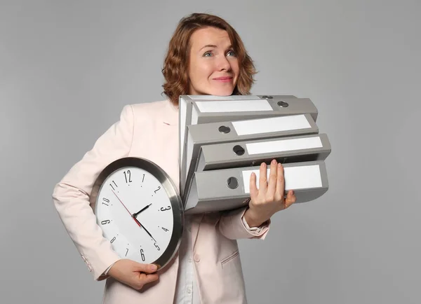 Manager donna con orologio e cartelle su sfondo grigio — Foto Stock