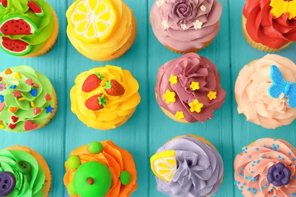 Gustosi cupcake colorati su sfondo di legno — Foto Stock
