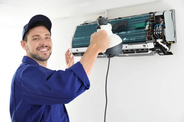 Mannelijke technicus schoonmaken van airconditioner binnen — Stockfoto