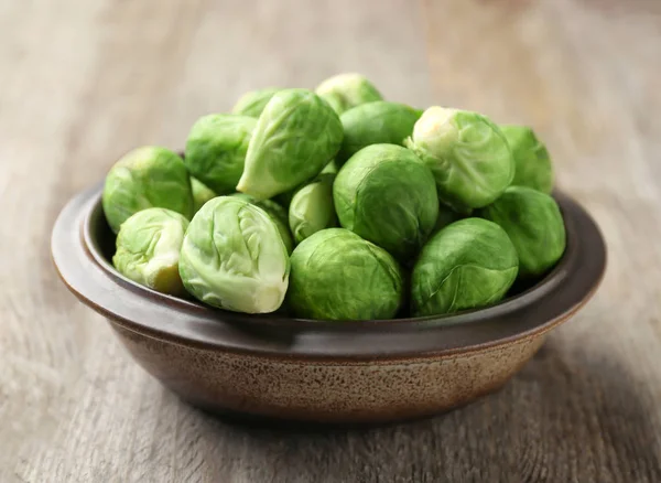 Cuenco con coles de Bruselas crudas sobre fondo de madera — Foto de Stock