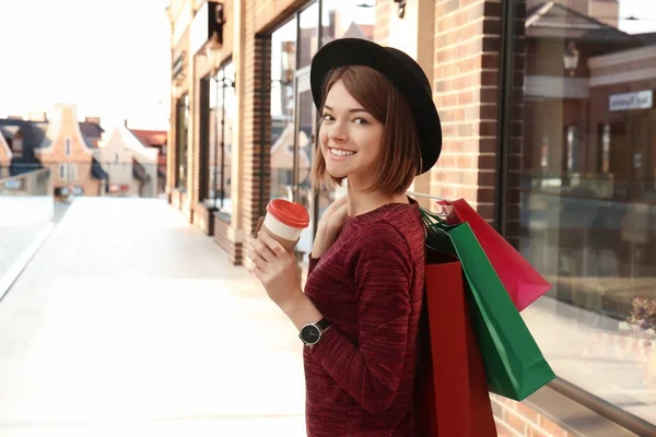 Belle femme avec des sacs à provisions et une tasse de café au centre commercial strip — Photo