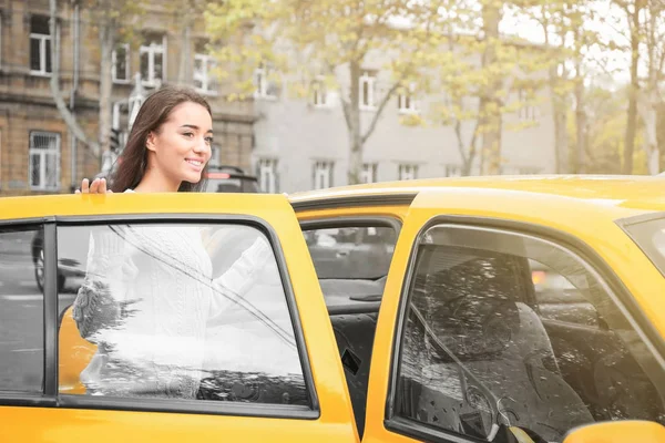 Młoda kobieta dostania się do samochodu taxi — Zdjęcie stockowe