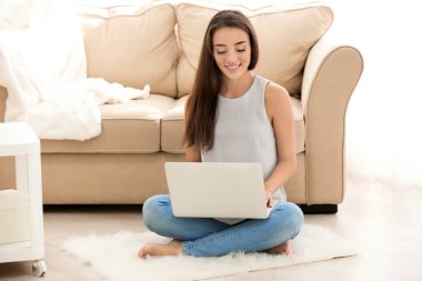 Kapalı yerde otururken dizüstü bilgisayar kullanan genç kadın