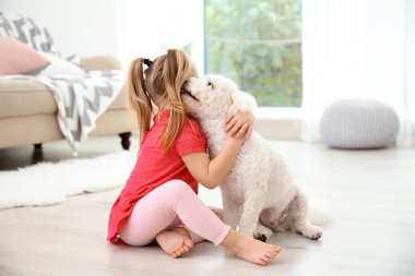 Adorable little girl with her dog at home clipart