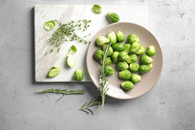 Taze çiğ Brüksel lahanası ve gri arka plan üzerinde otlar kompozisyonu