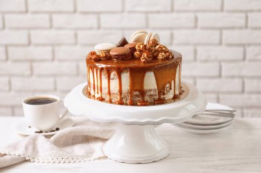 Duvara karşı masada lezzetli karamelli pasta ile stand