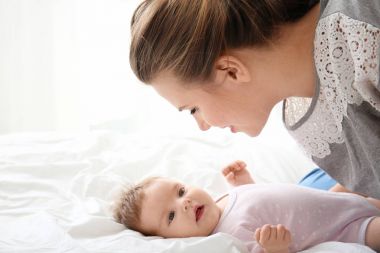 Genç anne ve evde yatakta şirin bebek