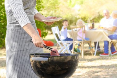 Adam açık havada mangal üzerinde lezzetli biftek pişirme