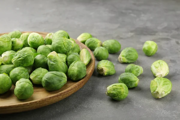 Houten plaat met verse rauwe spruitjes op tafel — Stockfoto